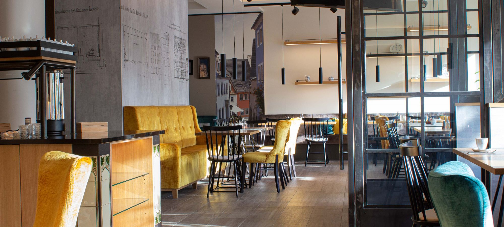Morgensonne fällt in das Frühstücksrestaurant des Hotels - elegante Sessel, Sofas, Stühle und das Buffet laden zum genießen und verweilen ein. Das moderne Ambiente mit seinen traditionellen Details verbindet Geschichte und sind nicht nur ein eyecatcher.